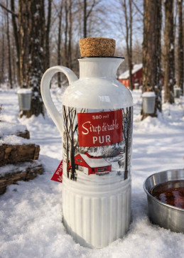 Cruche de sirop d'érable pur avec bouchon en liège, posée dans la neige au cœur d'une forêt d'érables en hiver.